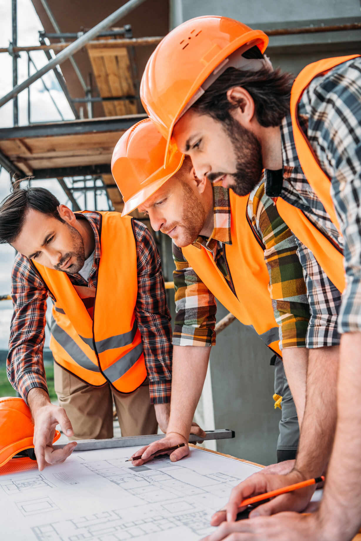 group of serious builders looking at building plan at construction site group of serious builders looking at building plan at construction site